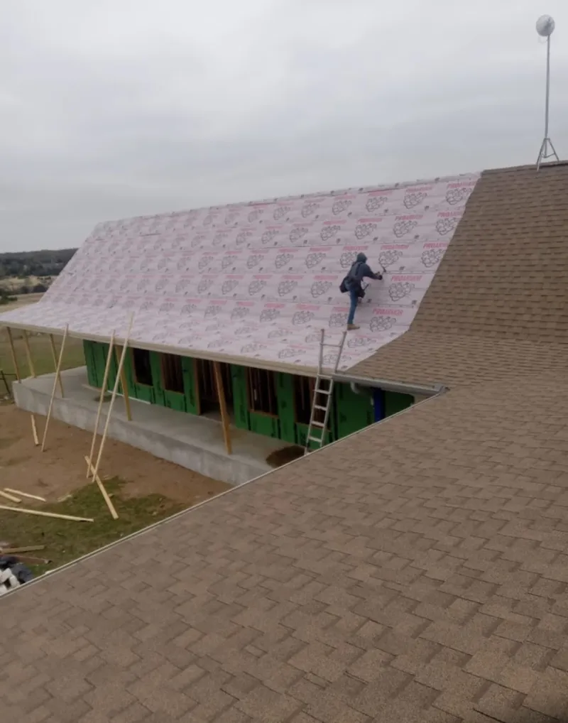 Worker preparing underlayment for a metal roof installation in Brazil